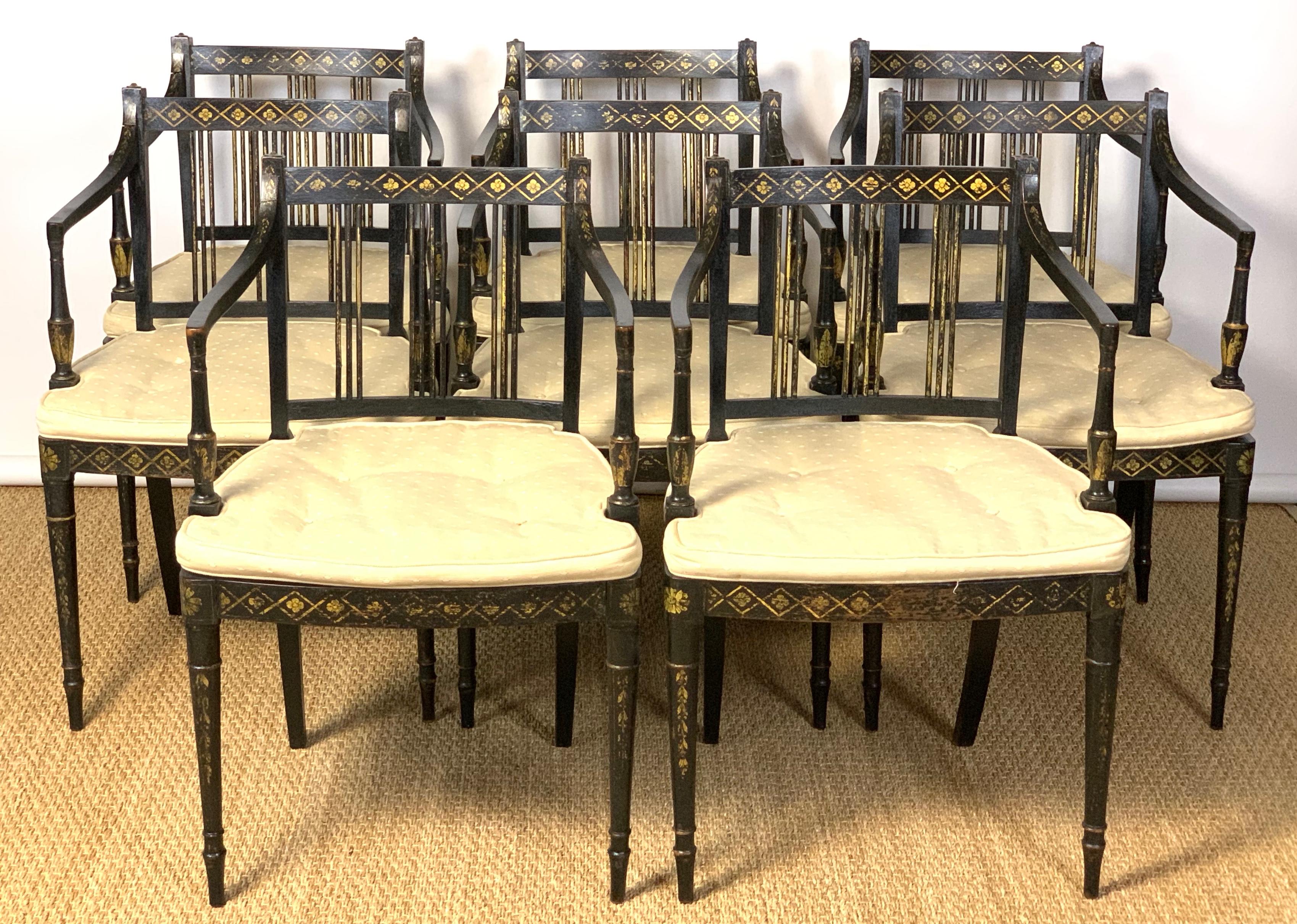 An exceptionally elegant and rare set of twelve early 19th Century. English Regency ebonized dining chairs comprising all arms. Each chair displays gilded decorations throughout with caned seats and custom fitted seat cushions.