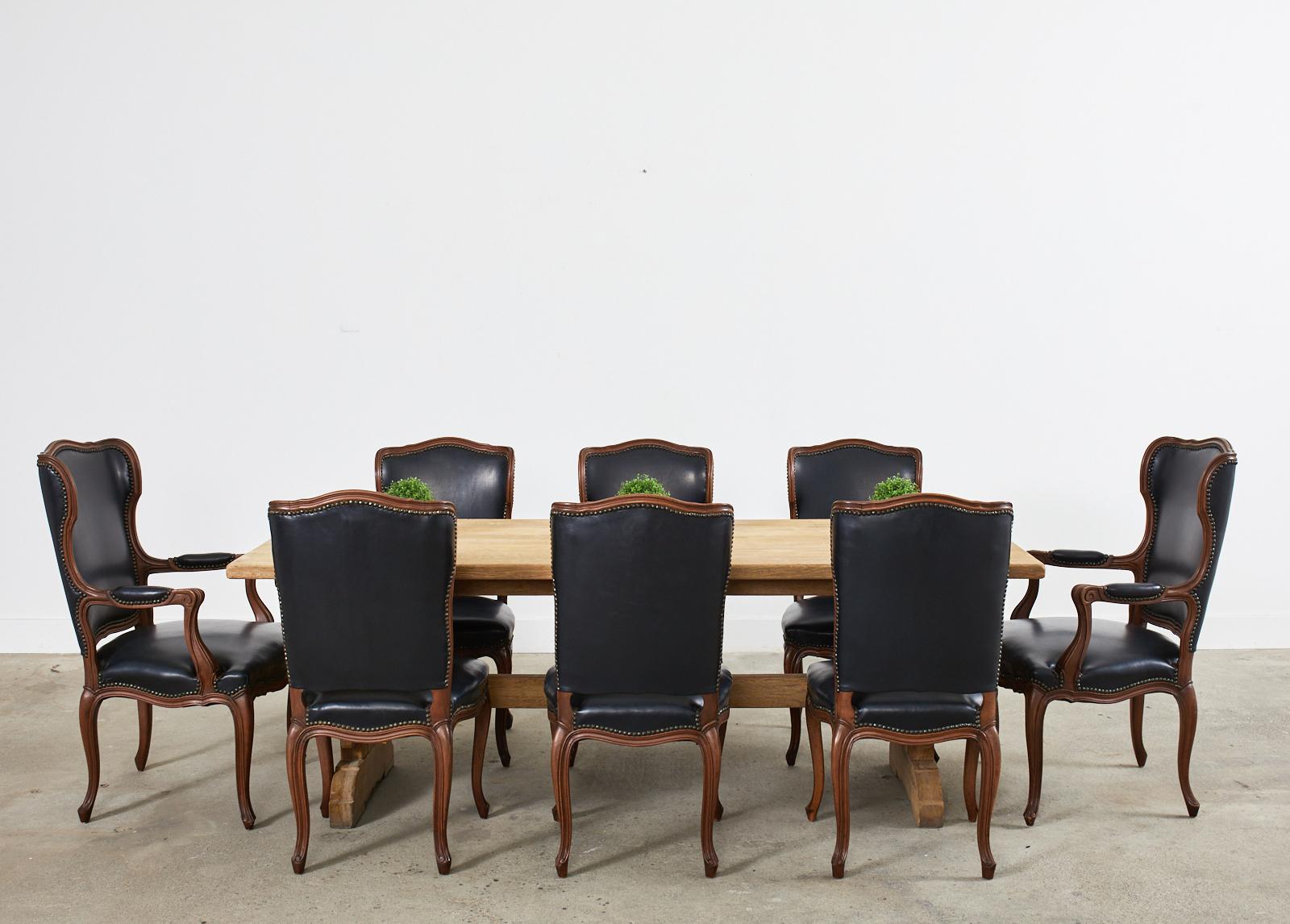 Grand set of twelve bespoke dining chairs a' oreilles or with ears crafted in the French Louis XV taste. The finely molded walnut frames have a humped crest on the back with small wings or ears. The set consists of ten side chairs and two large host