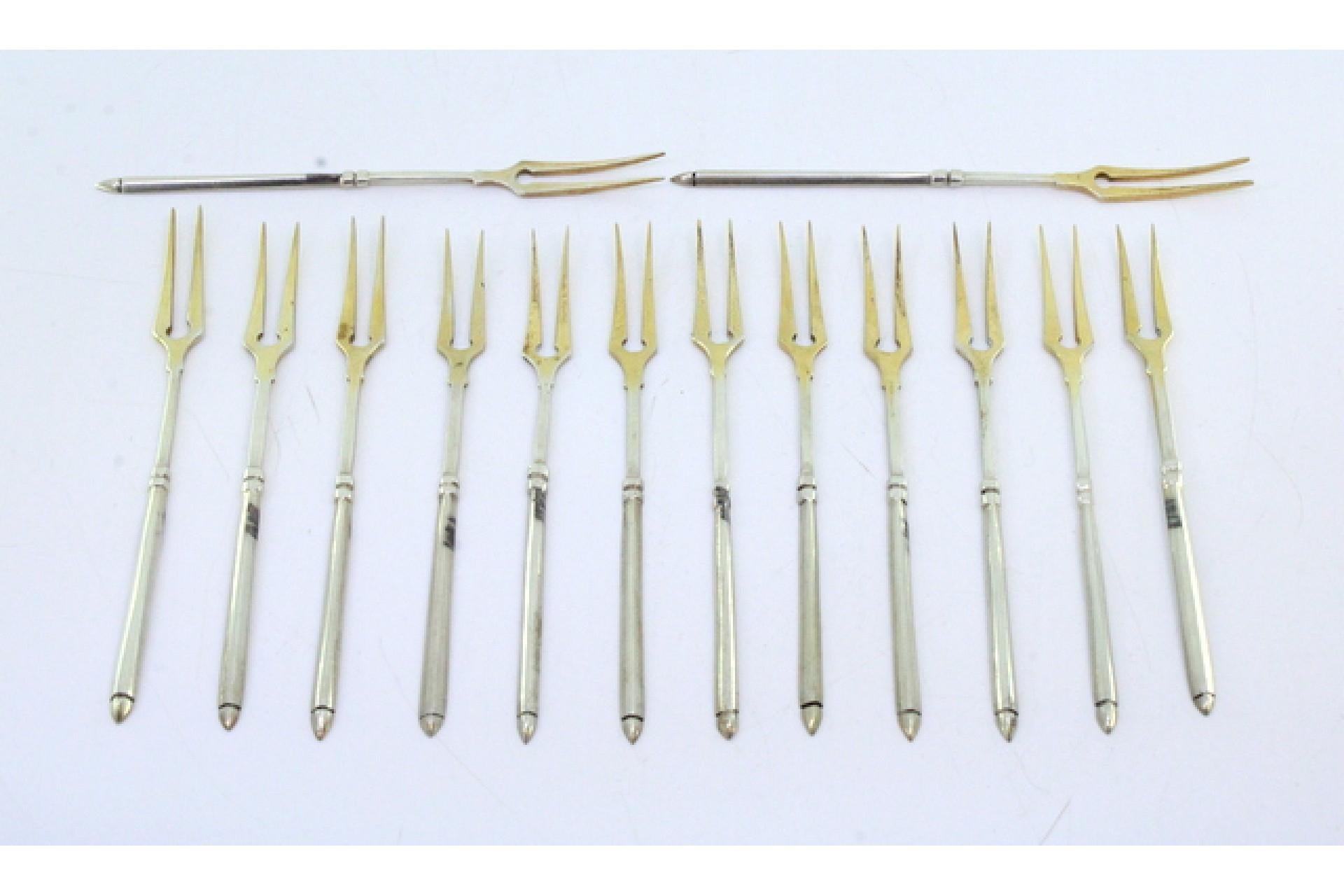 Description: Set of twelve gilded silver pickle forks with raised handles. Metal: Silver. Origin: Portuguese. Brand: Cabeça de escravo. Weight: 87.40 grams (Set of twelve forks). Dimensions: 11.8cm x 0.8cm. Content: 833/1000. Assay Mark: Yes,