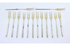 Set of twelve gilded silver pickle forks with raised handles