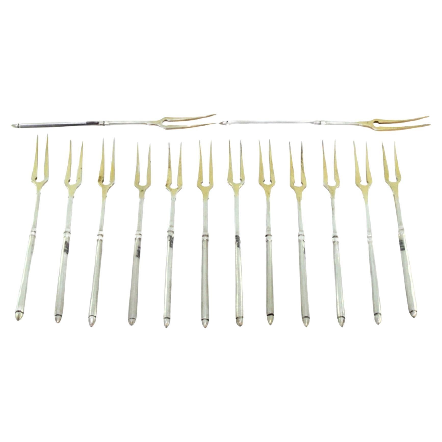 Set of twelve gilded silver pickle forks with raised handles