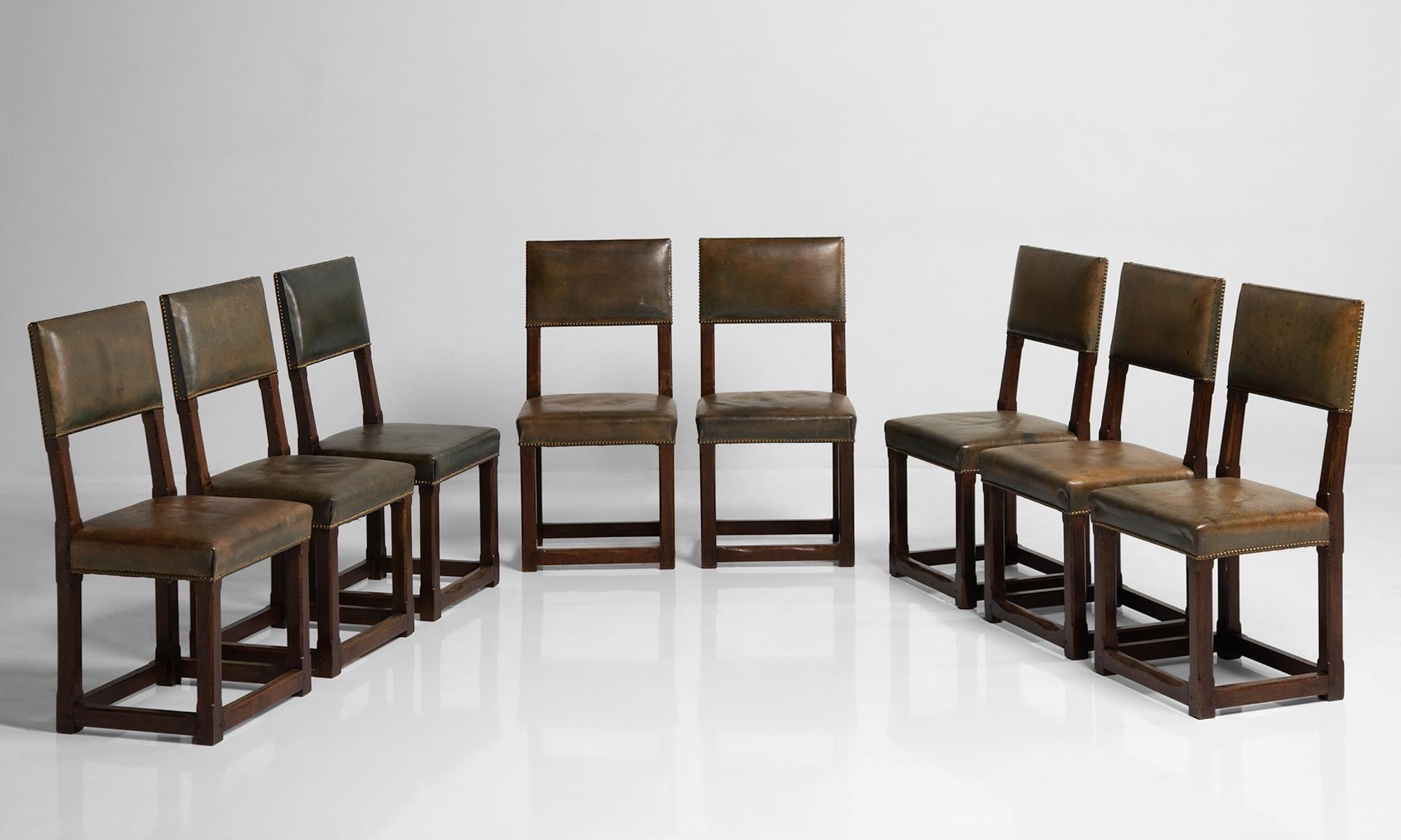 Set of twelve gothic oak dining chairs, England, circa 1880.

Oak frame with leather seat and back. Designed in the manner of Pugin, and originally used in the House of commons.

