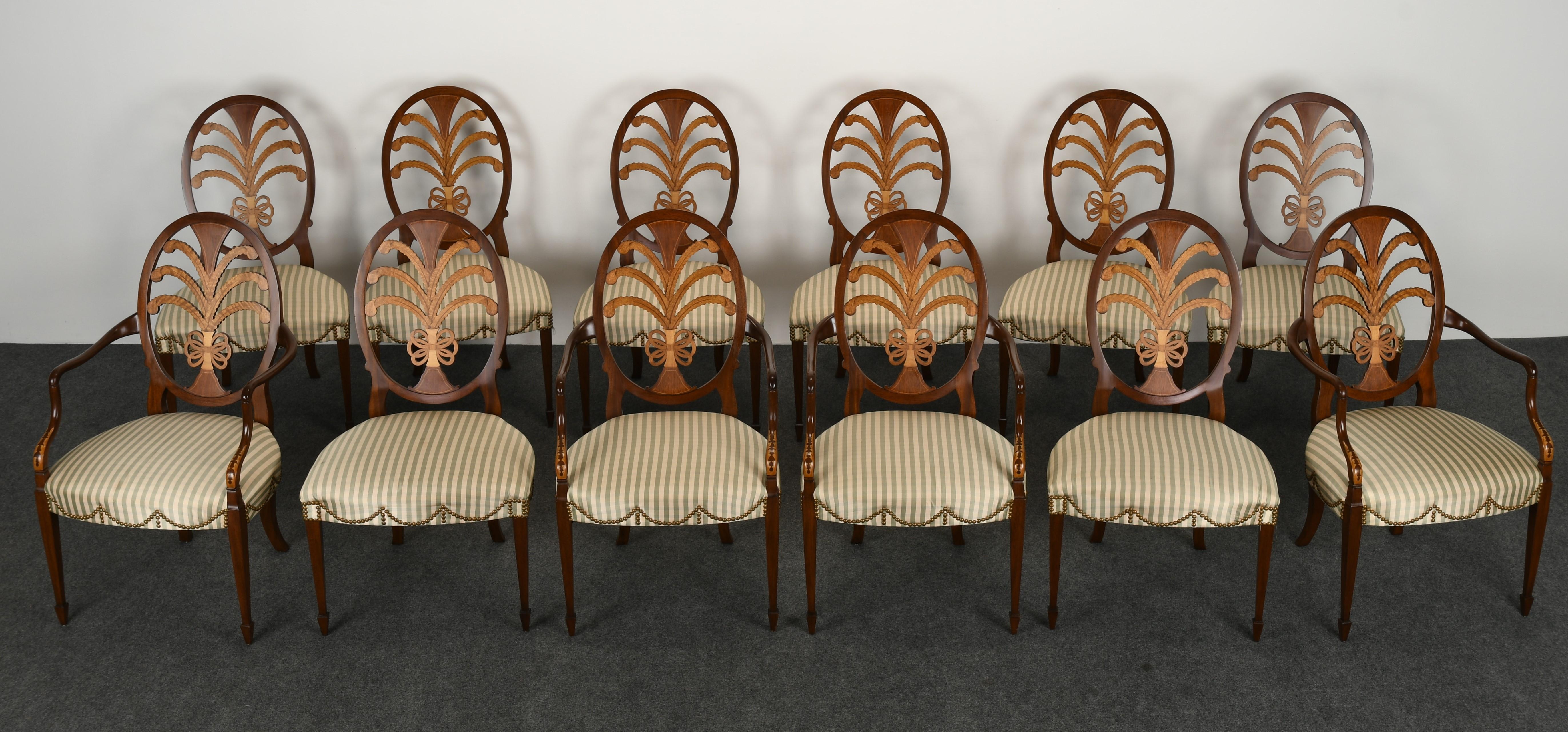 A fine pair of twelve Hepplewhite chairs by Karges. The chairs feature plumes and Satinwood inlay. The arms and spade feet are hand-carved with nail-head trim. There are 4 armchairs and 8 side chairs in this set. The chairs are in very good