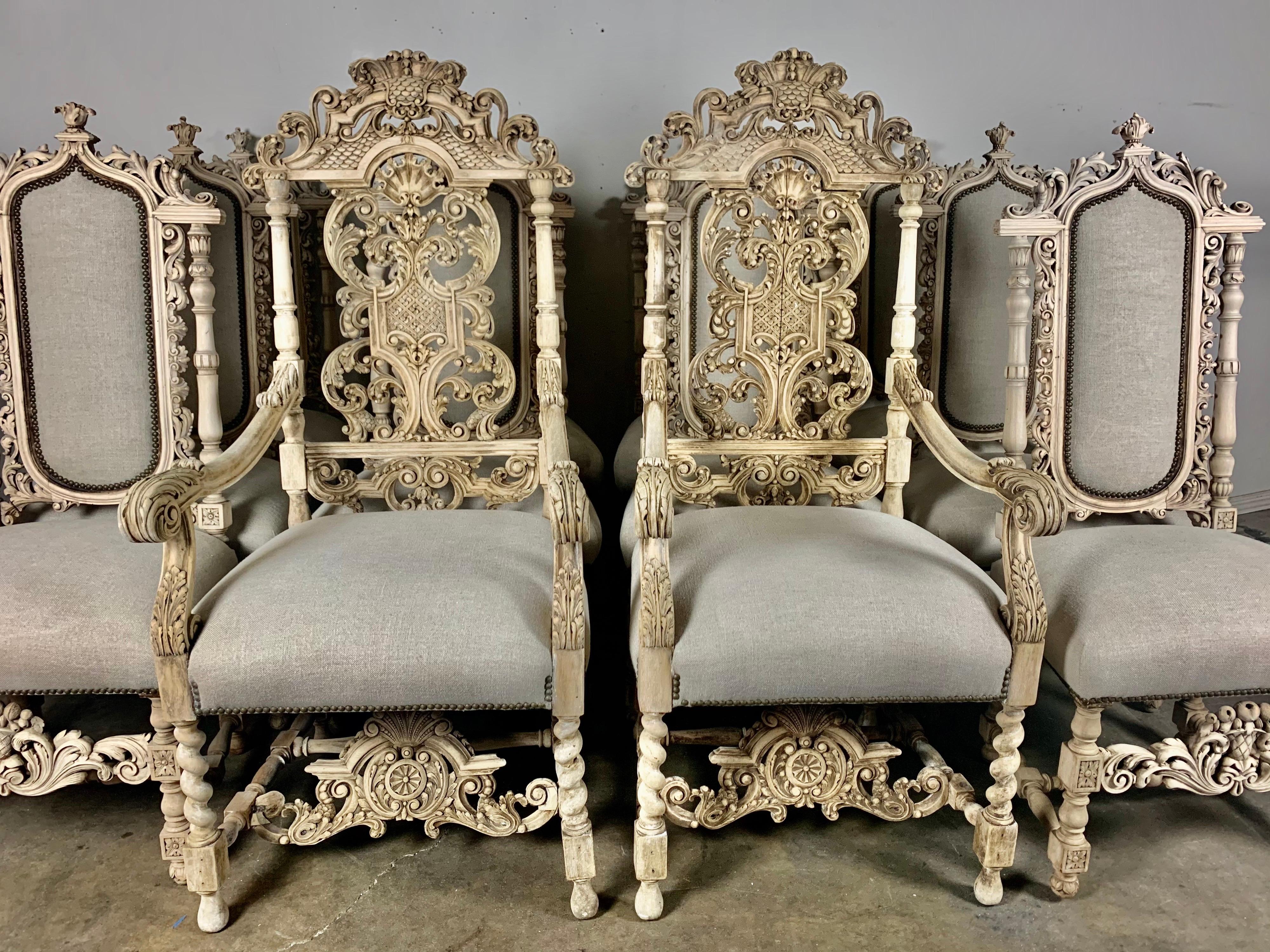 Set of twelve Italian hand carved Rococo style dining chairs that are newly reupholstered in a washed Belgium linen with nailhead trim detail. They are finely carved with intricate details of swirling acanthus leaves and more. Natural walnut