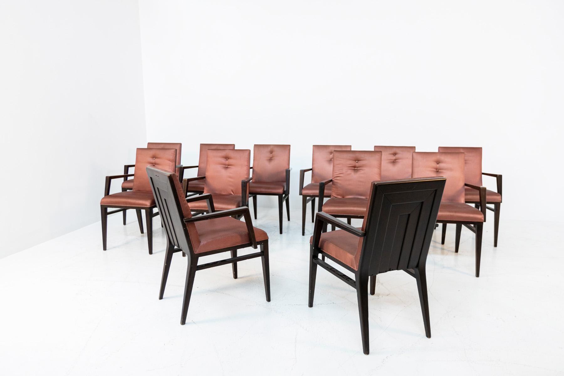 Elegant set of twelve Italian chairs from the 1950s. The set of chairs had been produced for the Italian naval manufacture. The chairs have a dark wood frame. While the seat and its back rest are made of cushion with dark pink silk lining. The