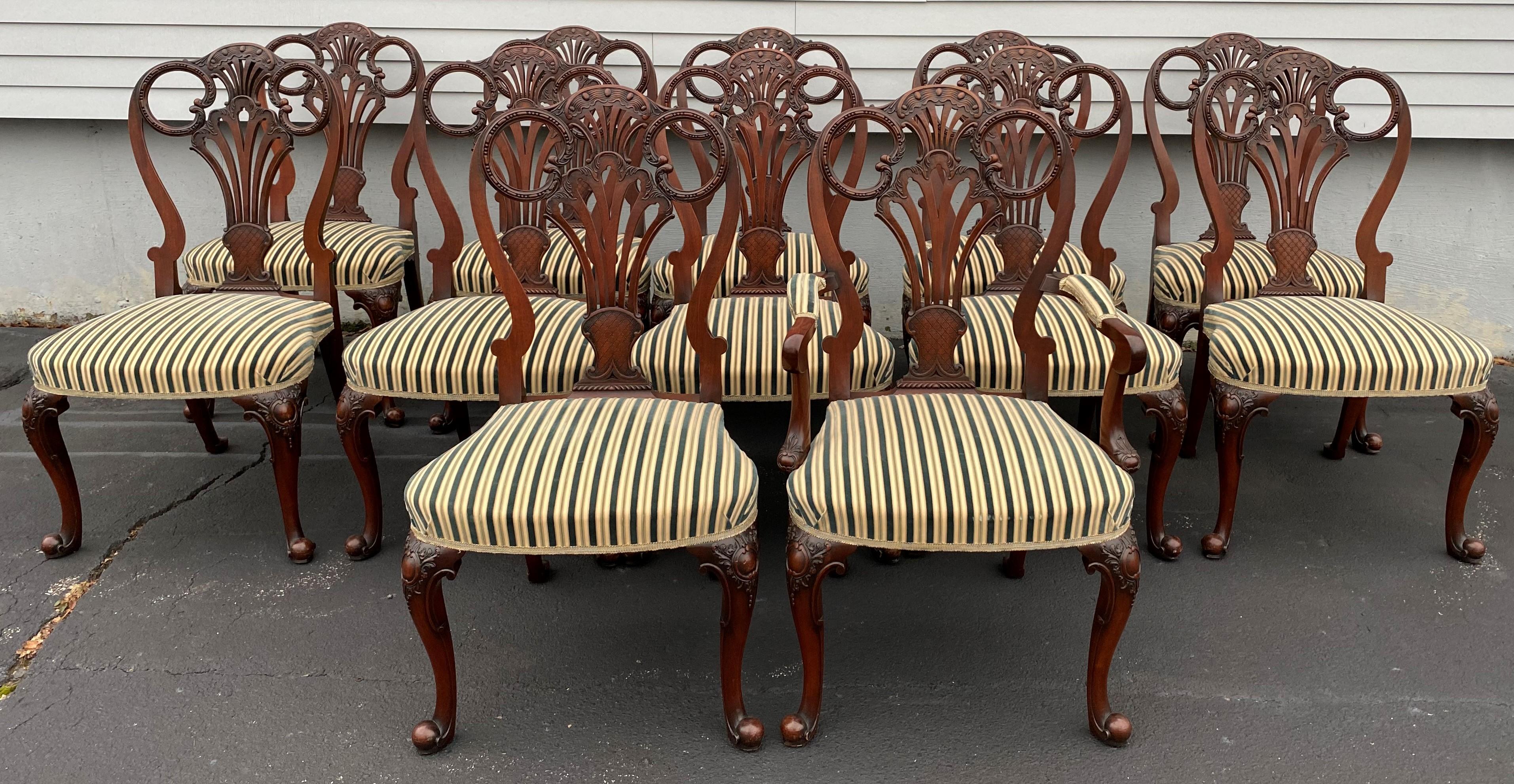 A beautiful set of twelve Italian custom mahogany Queen Anne style dining chairs, including 11 side chairs and one arm chair, with pierce carved back splats, cabriole legs terminating in scrolled ball feet, and finished with bold striped upholstery.