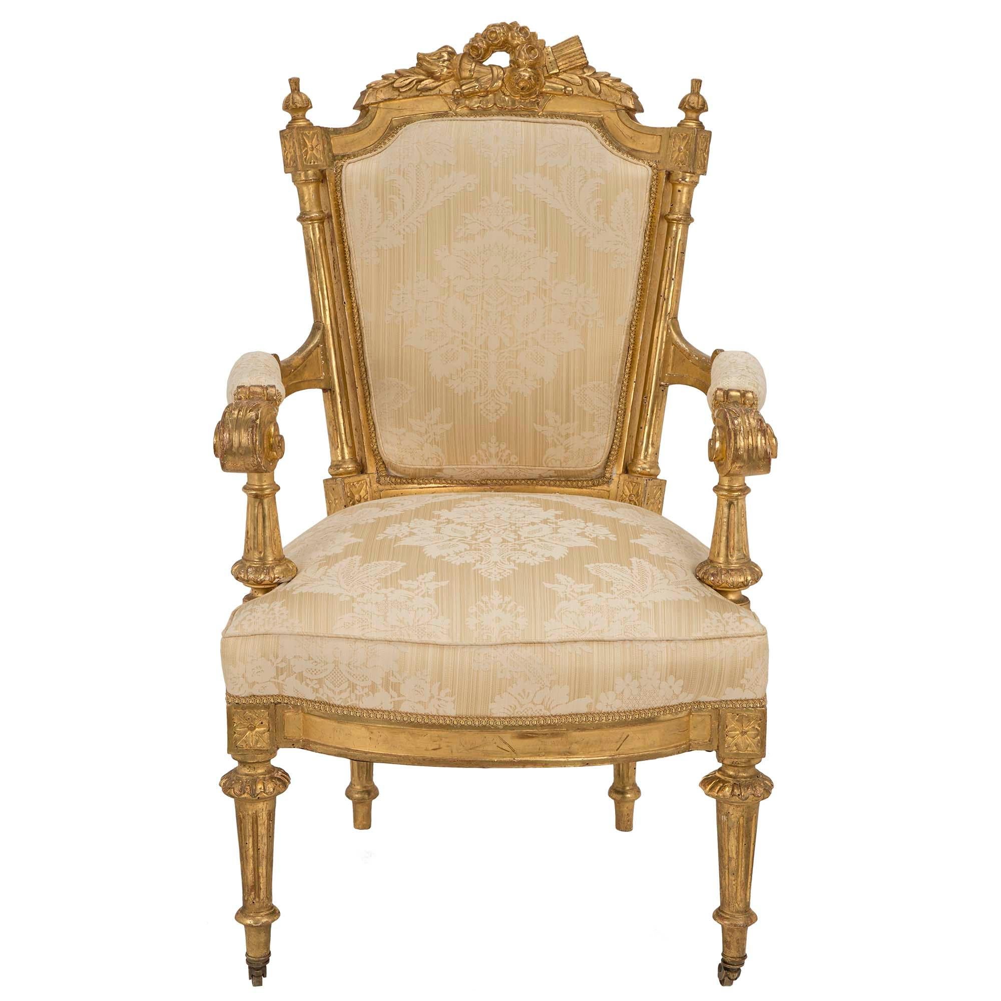 A spectacular and complete set of twelve Italian early 19th century Louis XVI st. giltwood dining chairs. Each seat is raised on tapered fluted legs with brass castors on the front and a foliate surround at the top. The generous sized seat, with