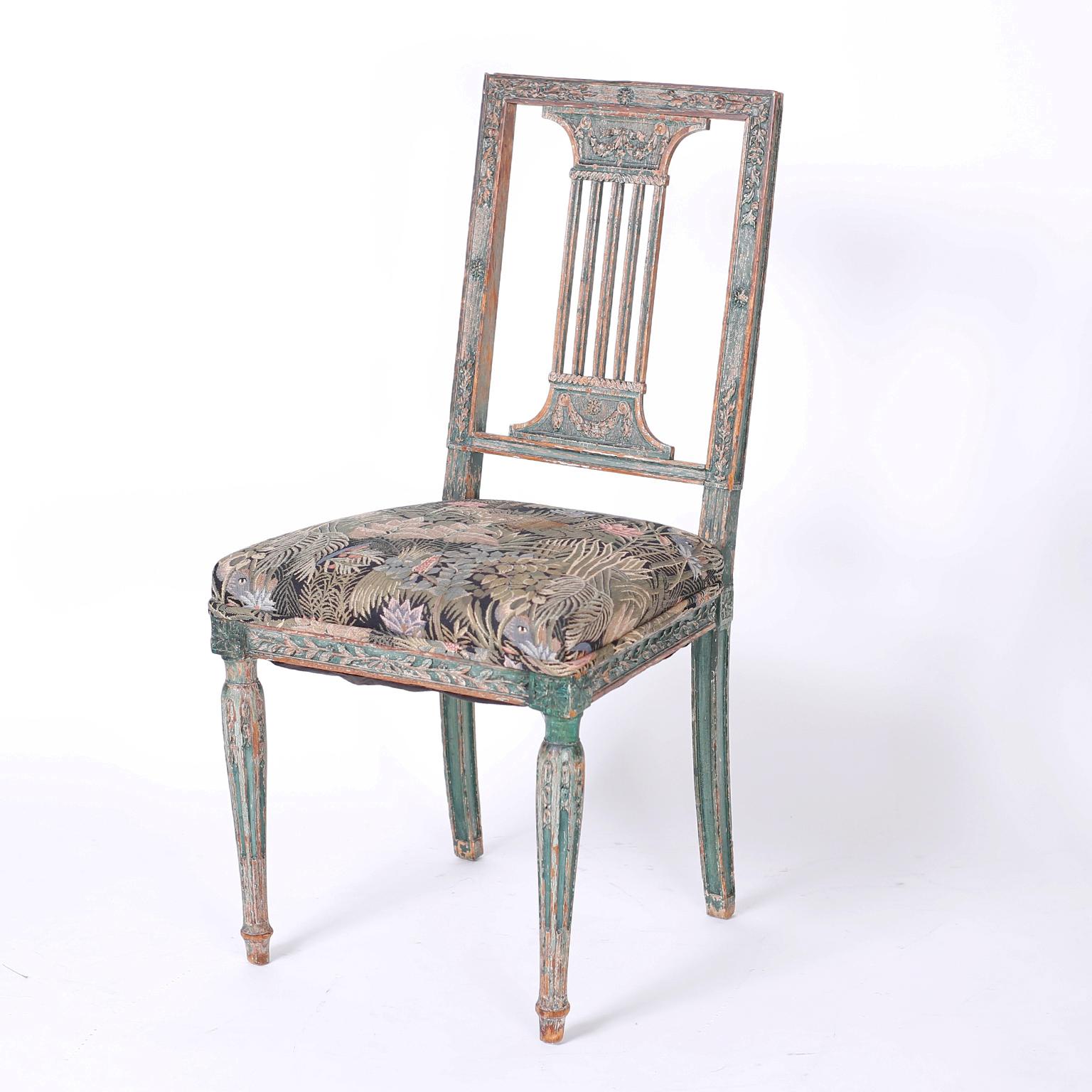 Set of antique twelve dining chairs with ten side chairs and two armchairs crafted in walnut with floral carvings and featuring back splats with a reference to Classic Greek architecture, perfectly worn green paint, and fluted tapered legs.

Side