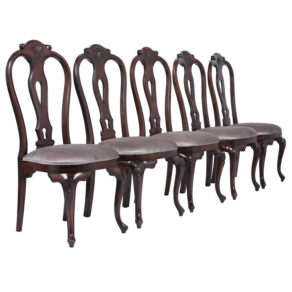 An extraordinary vintage set of twelve dining chairs handcrafted out of solid mahogany wood and are stained a rich dark mahogany color with a satin lacquered finish. This fabulous set features two armchairs & ten side chairs with finely frame