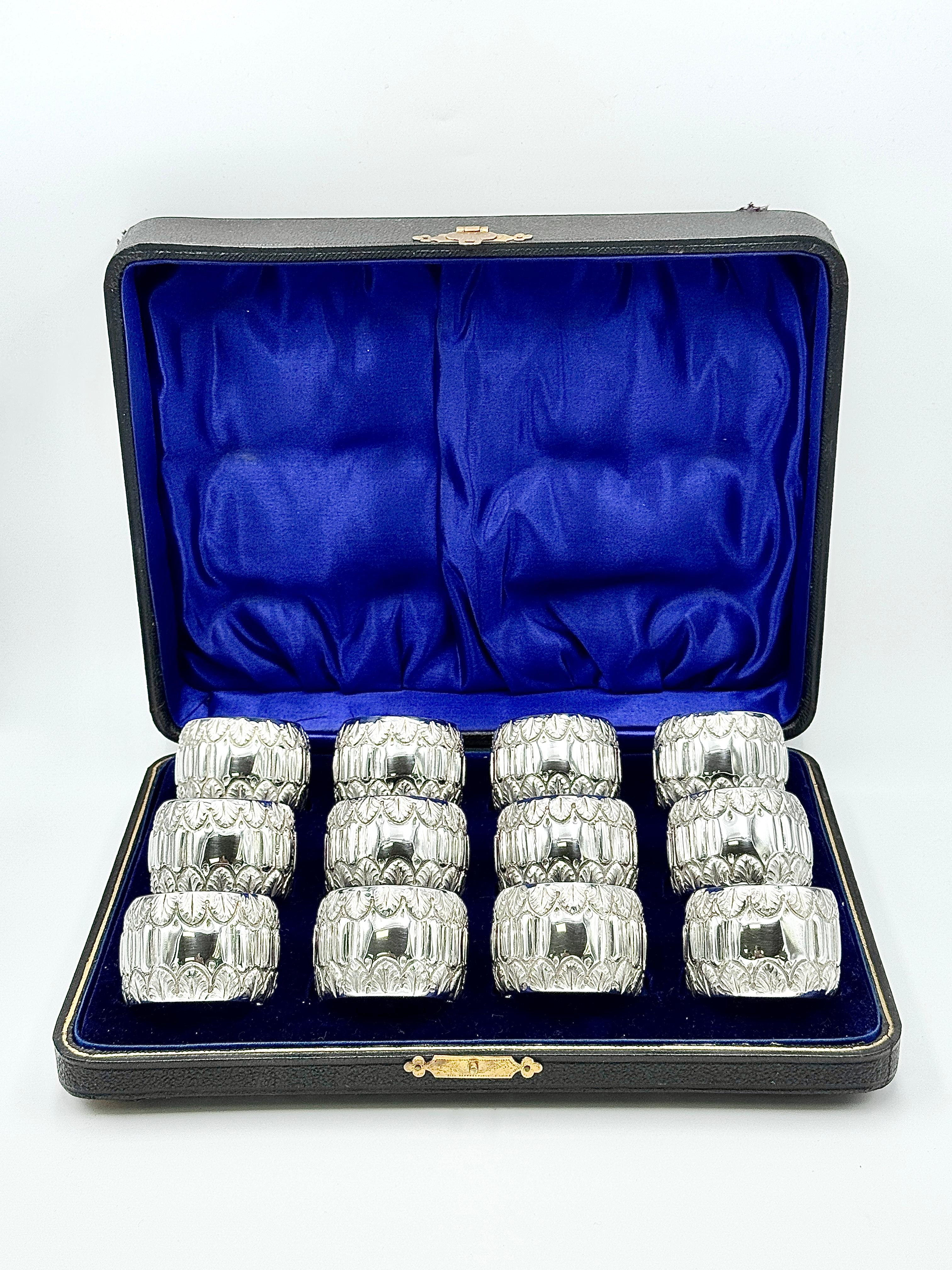 Ein Satz von zwölf silbernen Serviettenringen von Arthur Harris, jeder von runder Form mit kühnem Rillen- und Rollendekor und einer leeren Kartusche auf der Vorderseite. Präsentiert im originalen Etui mit königsblauem Samt und satinierter