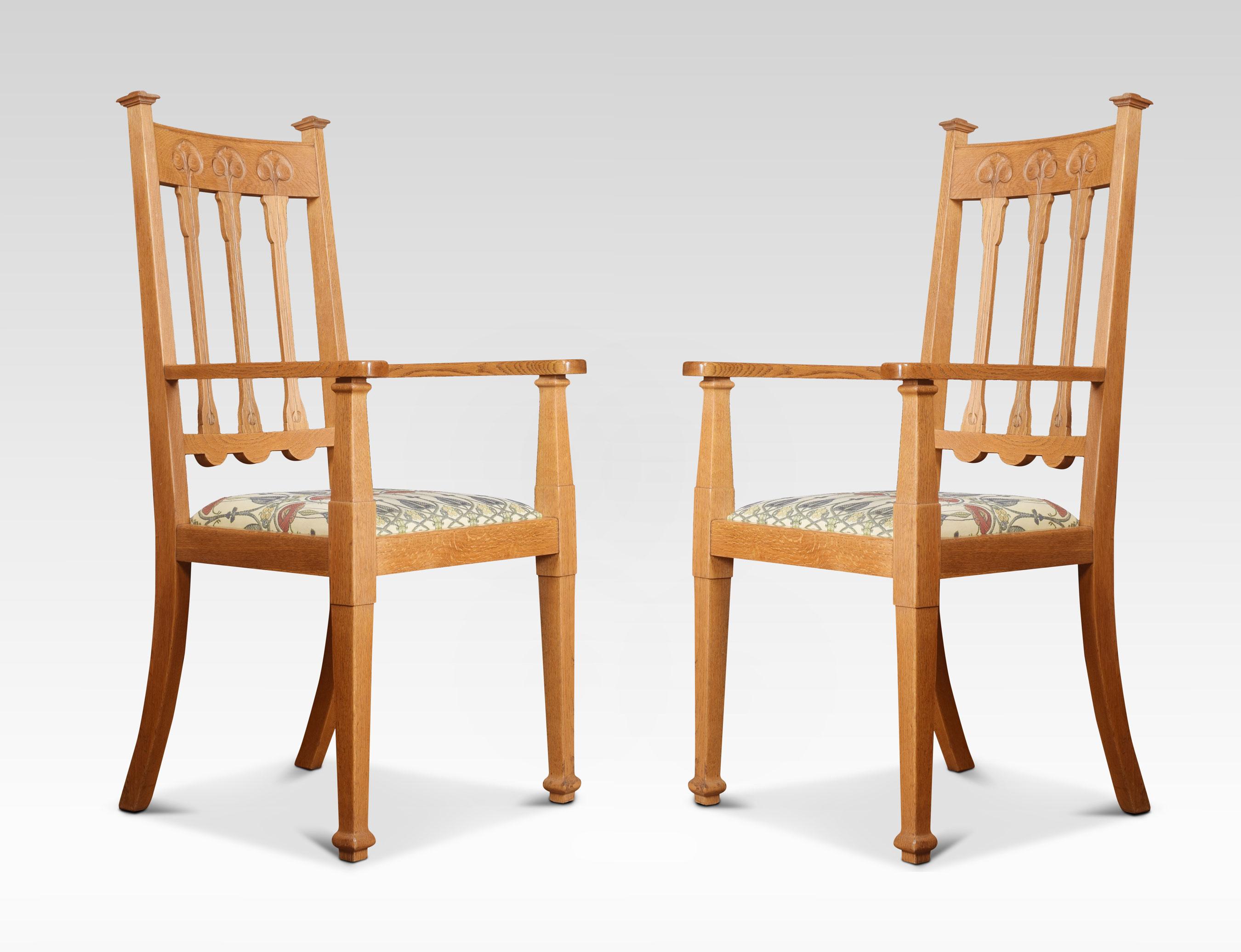 Set of twelve oak Arts and Crafts dining chairs. Comprising of two armchairs and ten chairs, having carved top rail above splat backs, the carvers with scrolling arms, above upholstered seats all raised up on tapering front legs.
Measures: