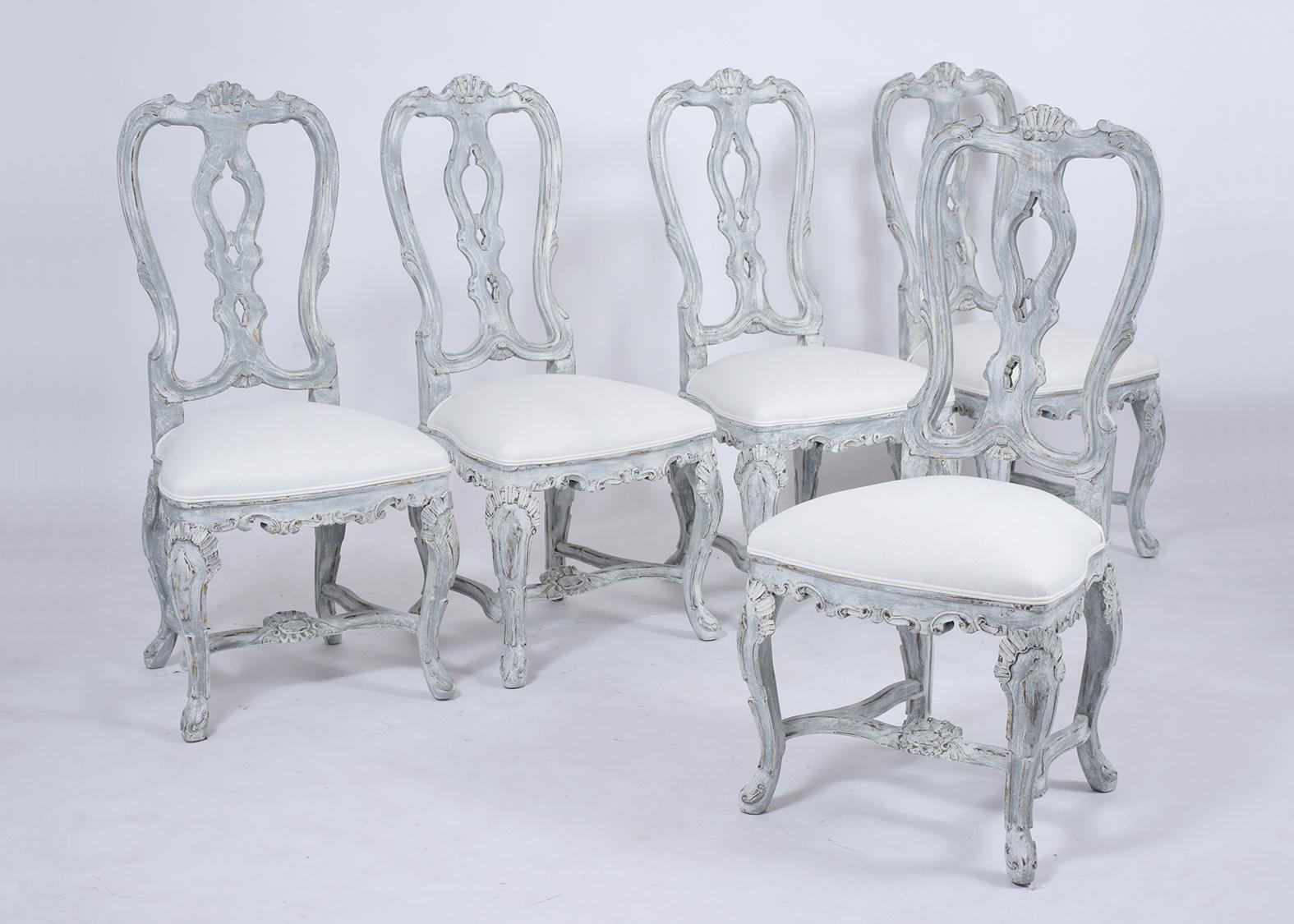 A remarkable antique set of twelve Italian dining chairs handcrafted out of maple wood featuring eleven side chairs and a single armchair with grotto-style carved details throughout the entire frame. The seat rest on sturdy carved stretched legs