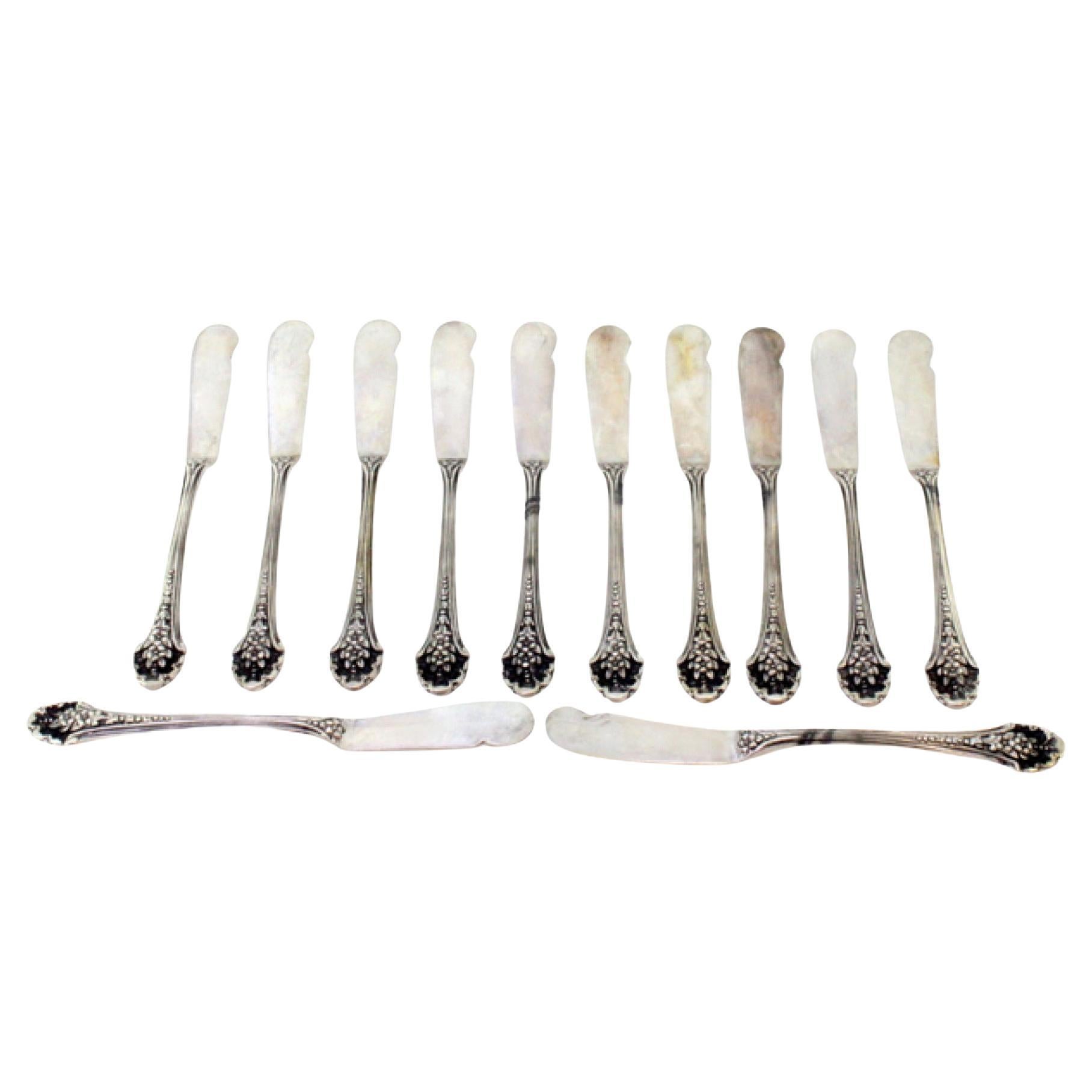 Set of twelve silver butter knives with reliefs along the handle