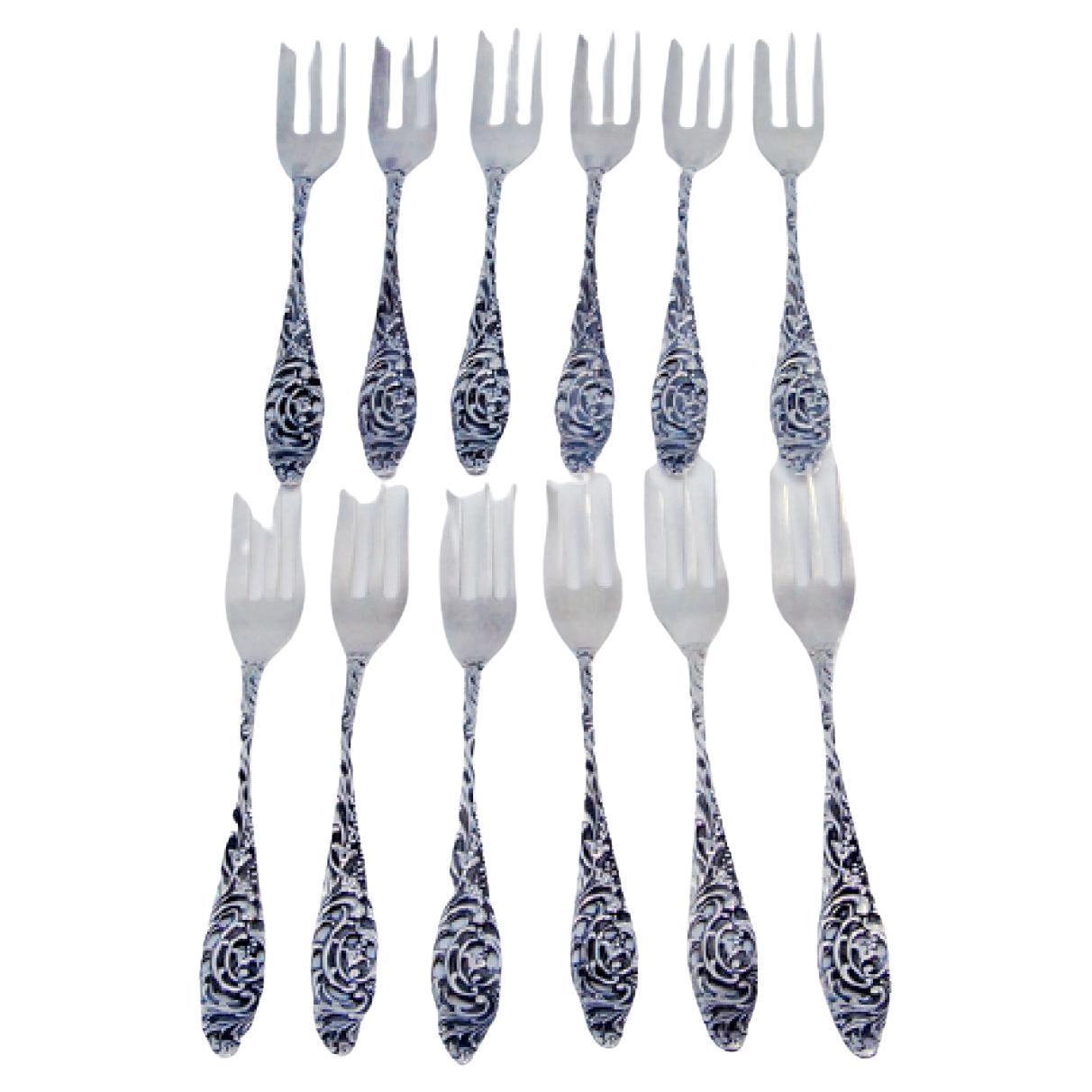 Set of twelve silver cake forks with embossed handles featuring plant motifs