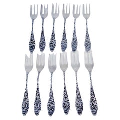Set of twelve silver cake forks with embossed handles featuring plant motifs