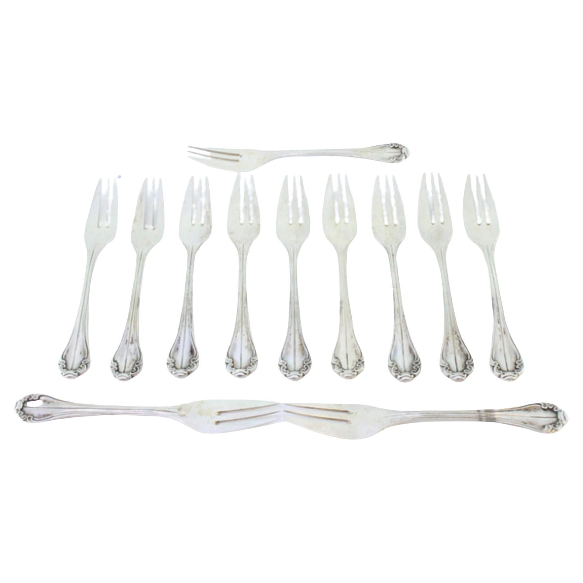 Set of twelve silver cake forks with trim and shells along the handles
