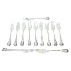 Set of twelve silver cake forks with trim and shells along the handles