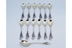 Set of twelve silver coffee spoons and sugar scoop with scalloped handles