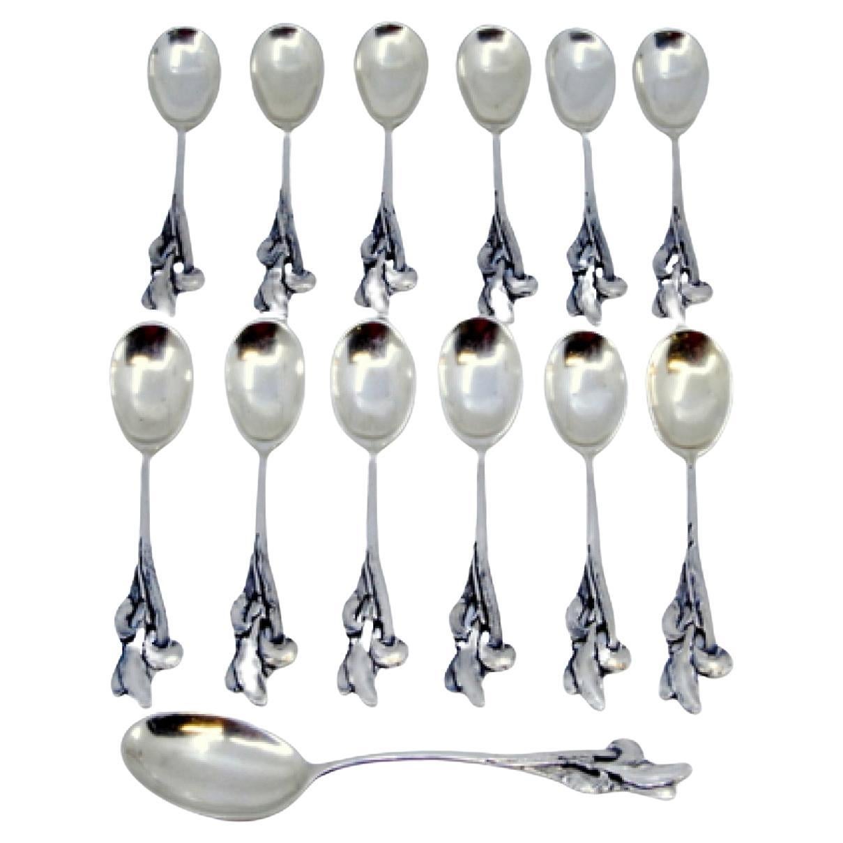 Set of twelve silver coffee spoons and sugar scoop with scalloped handles