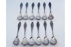 Set of twelve silver coffee spoons with handles cut into scrolls and shells