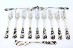 Set of twelve silver forks w/ reliefs on the handles surrounding monogram cards
