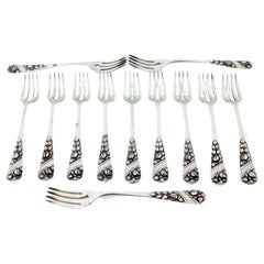 Set of twelve silver forks w/ reliefs on the handles surrounding monogram cards Set of twelve silver forks w/ reliefs on the handles surrounding monogram cards