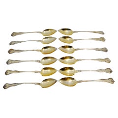 Juego de doce cucharillas de plata dorada con picos en las conchas y asas en relieve