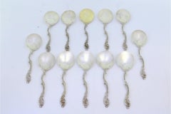 Set of twelve silver ice cream scoops with smooth shells and twisted handles
