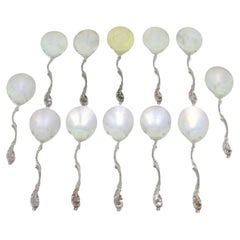 Set of twelve silver ice cream scoops with smooth shells and twisted handles