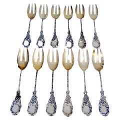 Set of twelve silver oyster forks with reliefs surrounding monogram cards
