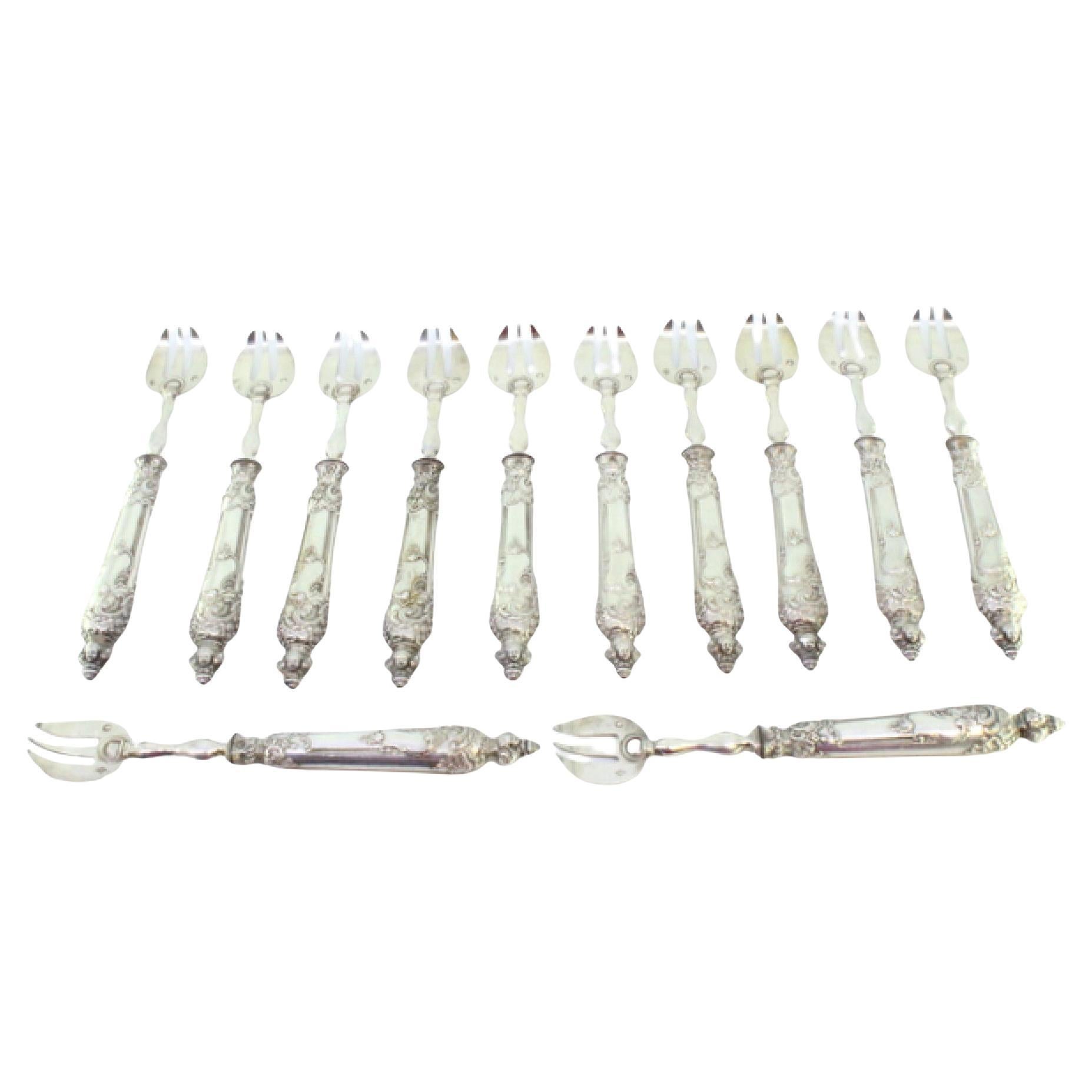 Set of twelve silver oyster forks with three tines and raised handles