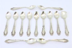 Set of twelve silver spoons & sugar shovel w/ reliefs & grooves on the handles