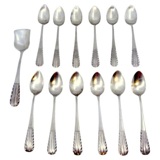 Set of twelve silver tea spoons and sugar shovel with raised handles