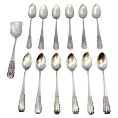 Set of twelve silver tea spoons and sugar shovel with raised handles