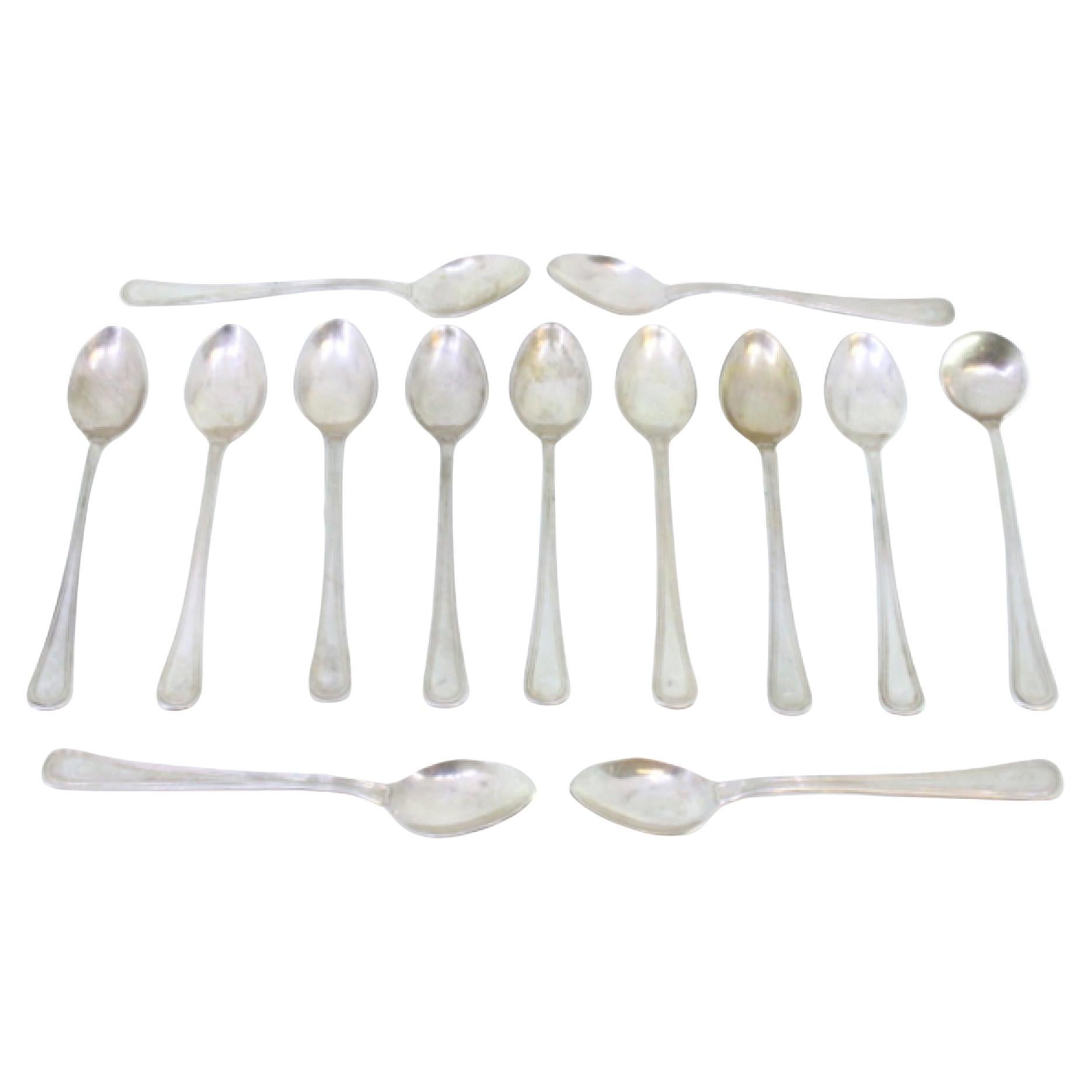 Set of twelve silver teaspoons and sugar ladle with grooves along the handles
