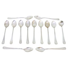 Set of twelve silver teaspoons and sugar ladle with grooves along the handles