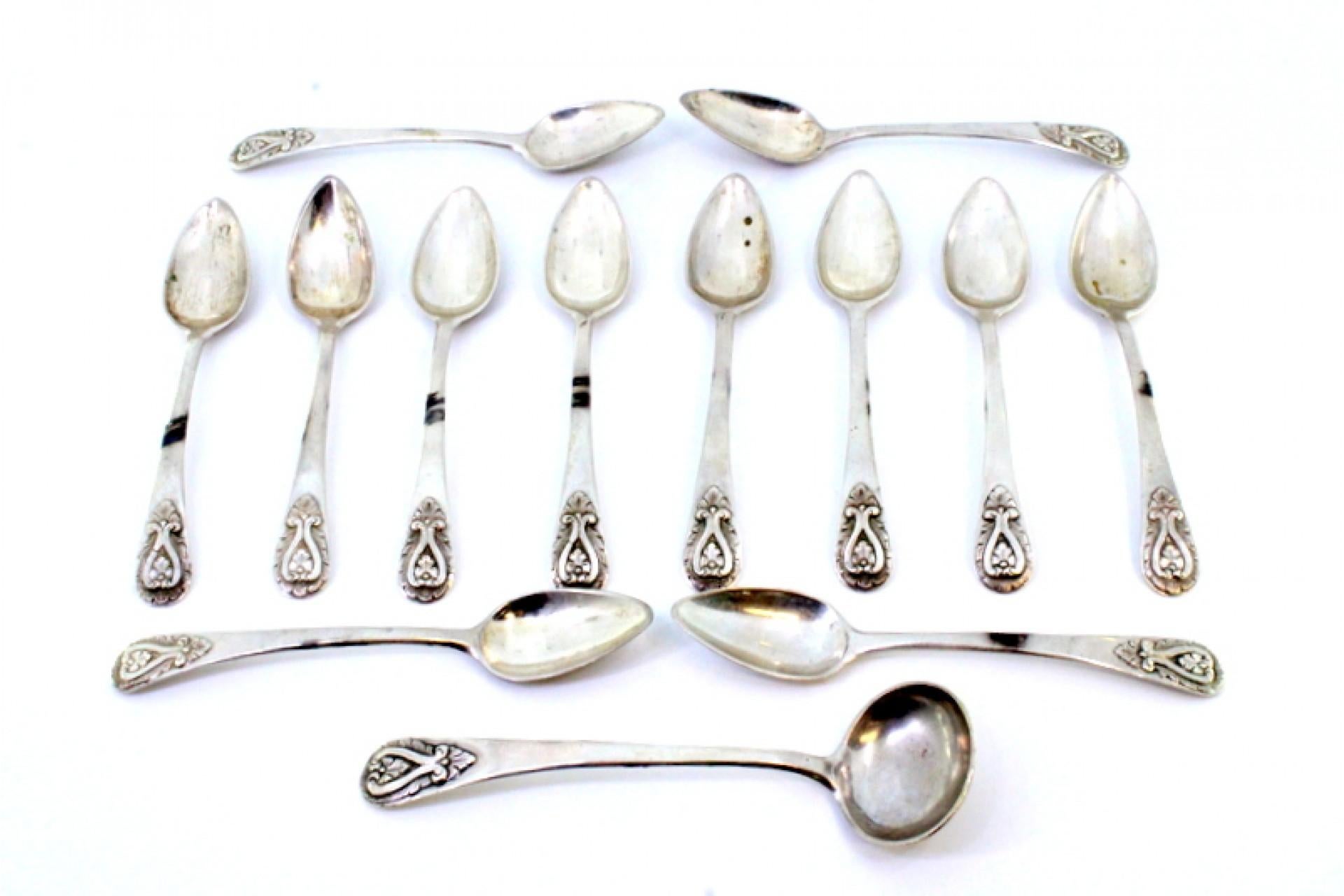 Description: Set of twelve silver teaspoons and sugar ladle with reliefs on the handles. Metal: Silver. Origin: Portuguese. Brand: Porto Coroa. Weight: 258.14 grams (Set of twelve spoons and ladle). Dimensions: Ladle - 13.5x3.7cm Spoon - 13x2.5cm.
