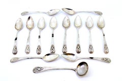 Set of twelve silver teaspoons and sugar ladle with reliefs on the handles