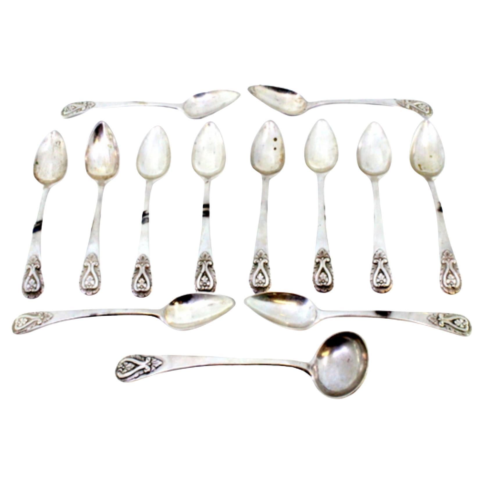 Set of twelve silver teaspoons and sugar ladle with reliefs on the handles