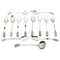 Set of twelve silver teaspoons and sugar ladle with reliefs on the handles