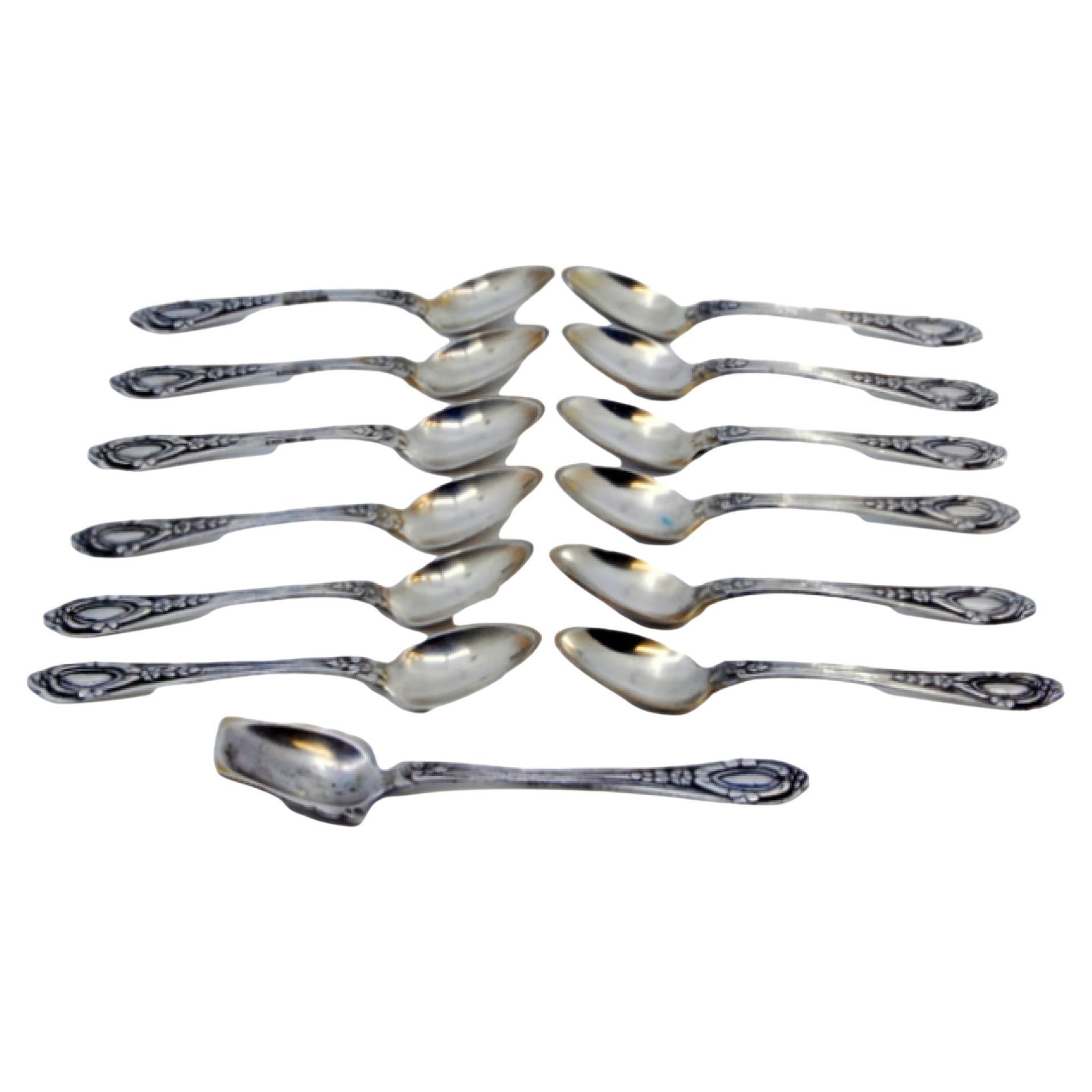 Set of twelve silver teaspoons and sugar shovel with reliefs on the handles