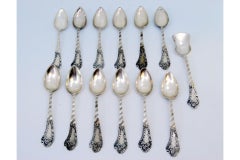 Set of twelve silver teaspoons & sugar scoop w/ wavy handles & monogram cards