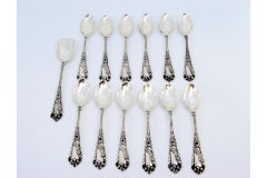 Set of twelve silver teaspoons & sugar shovel w/ floral reliefs on the handles
