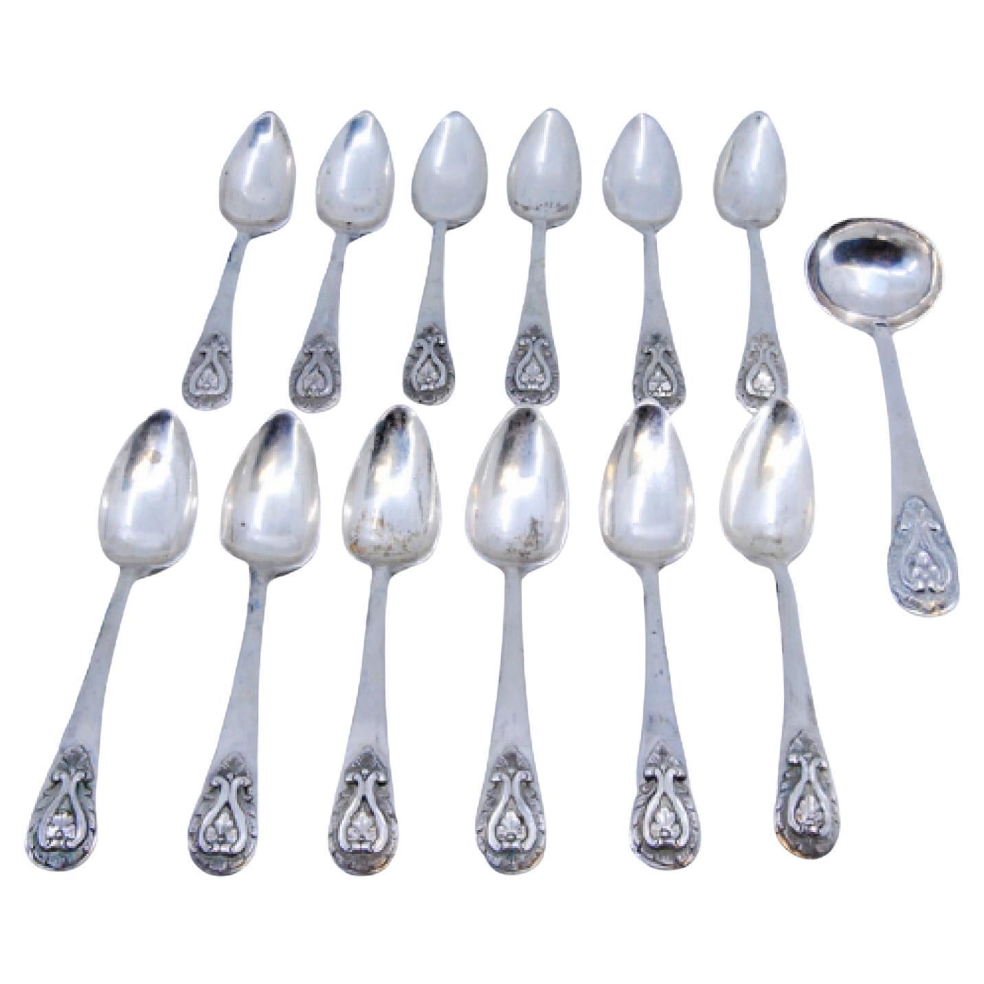 Set of twelve silver teaspoons with sugar scoop and reliefs on the handles