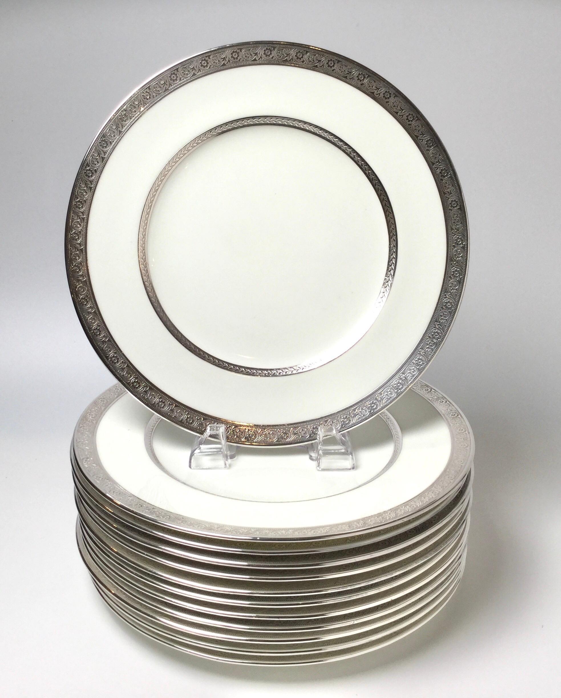 Set of 12 sterling overlay service plates. Ivory white porcelain with sterling silver banding. Made by Cauldon England. Retailed by Ovington Bros. NYC. Measure: 10 3/4