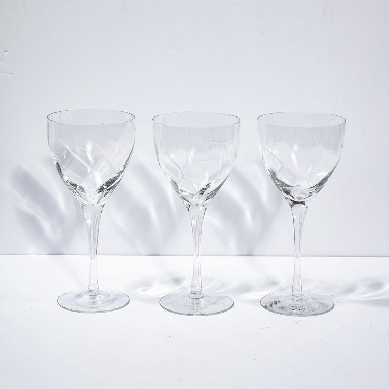 This stunning set of twelve wine glasses were realized by the fabled American company Tiffany & Co. They feature circular bases; cylindrical stems (that flare slightly at their apex); and rounded bodies with subtle channeling detailing at a slight