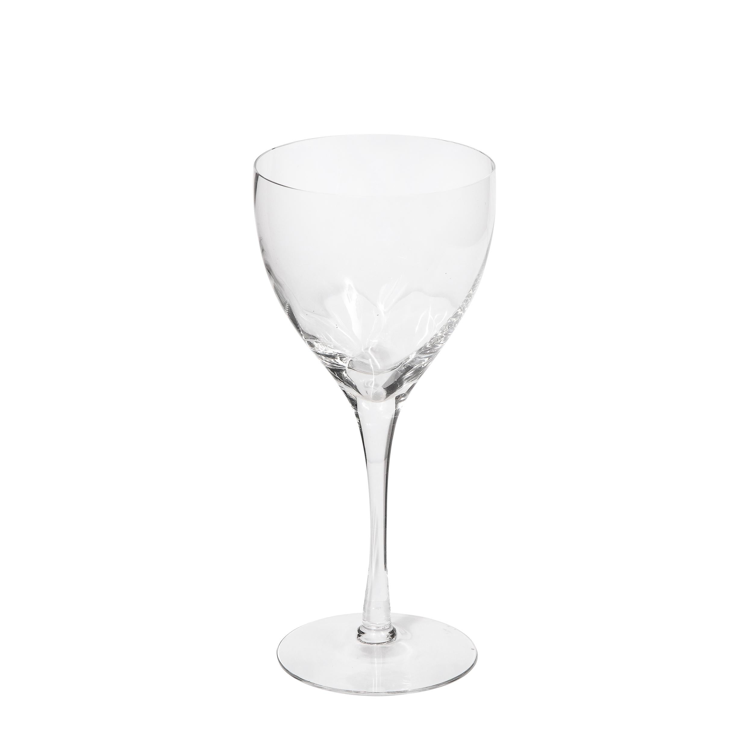 This stunning set of twelve wine/ water glasses were realized by the fabled American company Tiffany & Co. They feature circular bases; cylindrical stems (that flare slightly at their apex); and rounded bodies with subtle channeling detailing at a
