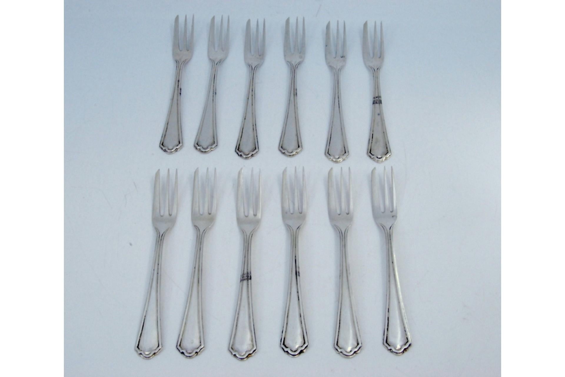 Description: Set of twelve three-pronged silver cake forks with grooved handles. Metal: Silver. Origin: Portuguese. Brand: Cabeça de escravo. Weight: 328.41 grams. Dimensions: 13.5x1.6cm. Content: 833/1000. Assay Mark: Yes, between 1938 and 1984.