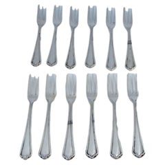 Set of twelve three-pronged silver cake forks with grooves on the handles