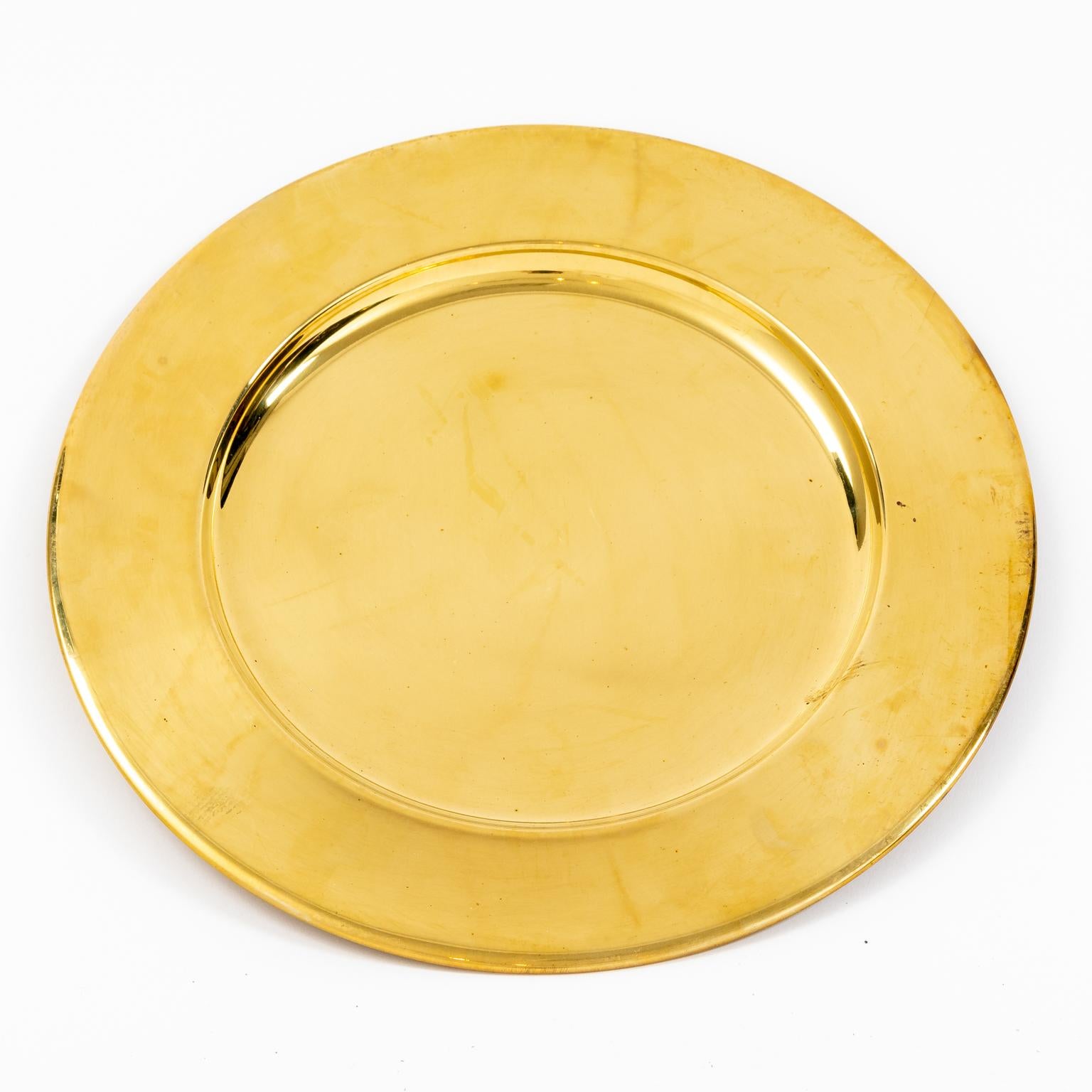 Set of twelve vintage 12.00 inch brass charger plates, circa mid-20th century. The brass is bright and shiny with light handling, these appear to have never been used. Please note of wear consistent with age including minor wear, slight scratches,
